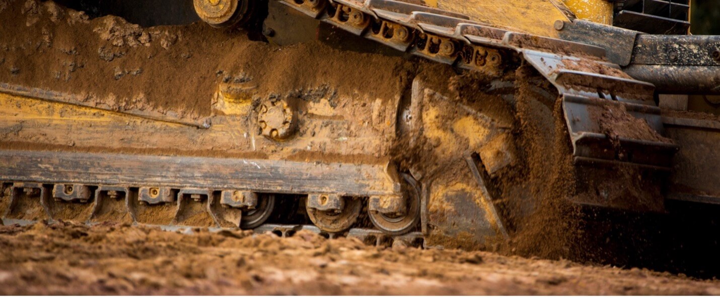 Close-up of a dozer’s muddy Cat® Steel Undercarriage with steel tracks.